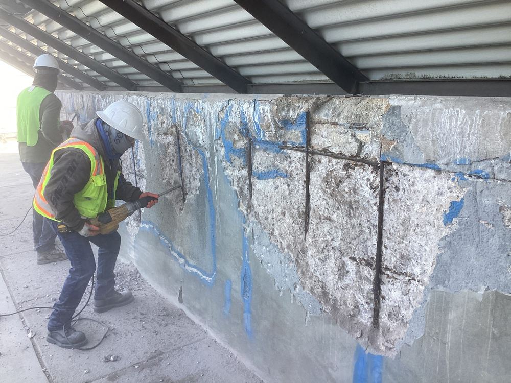 Cooling tower basin wall with deteriorated concrete removed down to the rebar, before repair